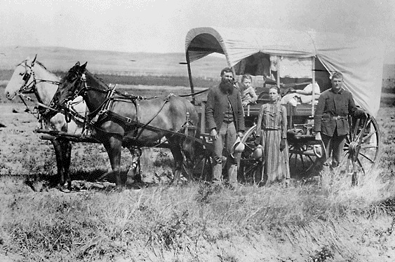 A family poses with the wagon in which they live and travel daily during their pursuit of a homestead, 1886.